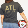 woman wearing game day shirt and holding soccer ball