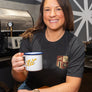 woman smiling while holding mug of coffee and wearing game day shirt