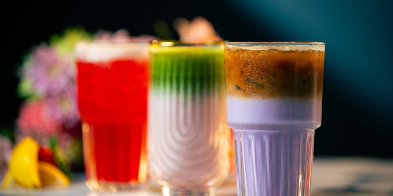 three colorful drinks in glasses on a floral background
