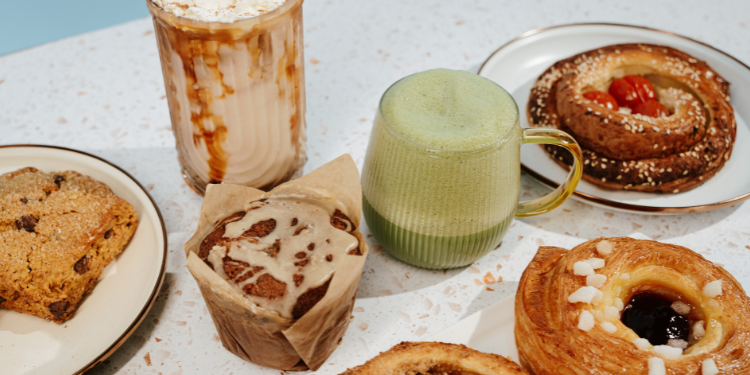 pastries on plates with two drinks on speckled counter
