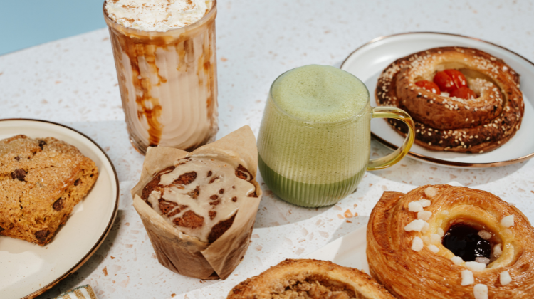 pastries on plates with two drinks on speckled counter