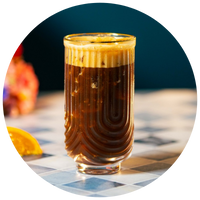 Glass of layered coffee drink on a checkered tablecloth with blurred background