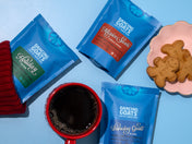 Dancing Goats coffee packages with a red mug and cookies on a blue background