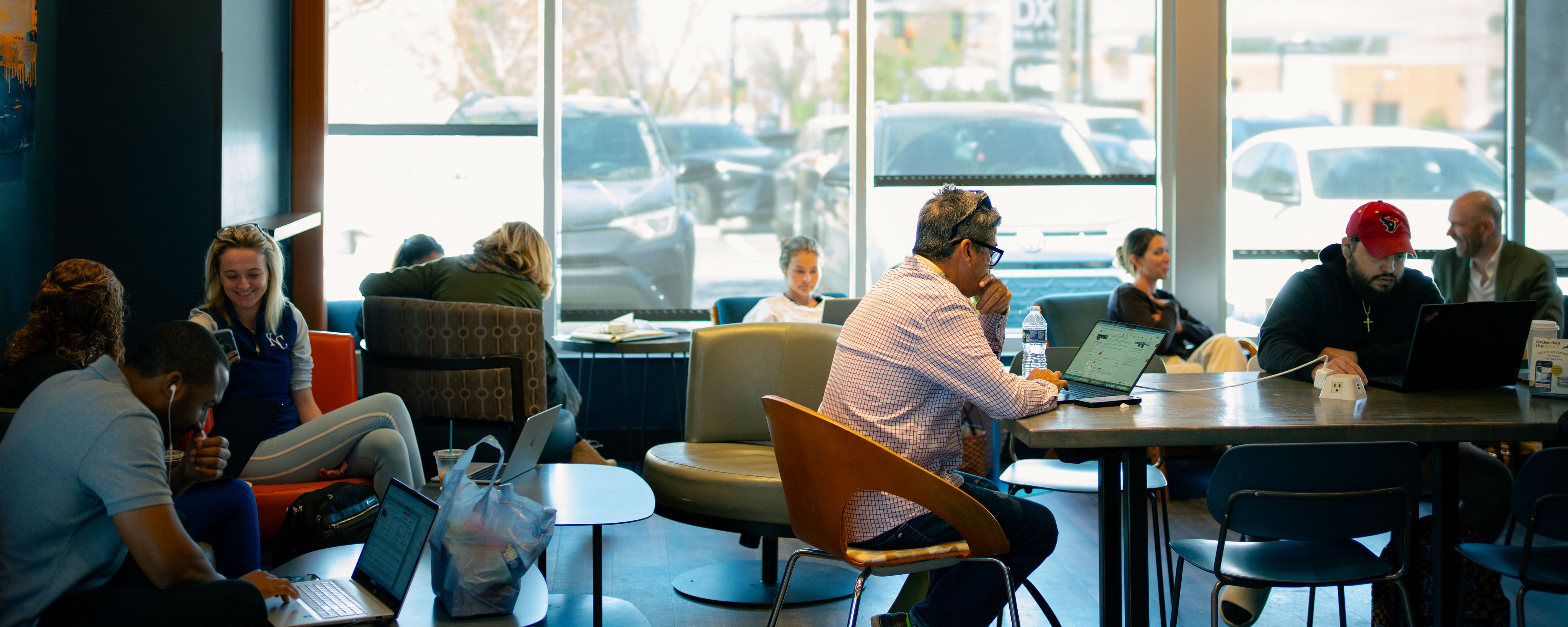People working on laptops in a modern office setting with large windows.