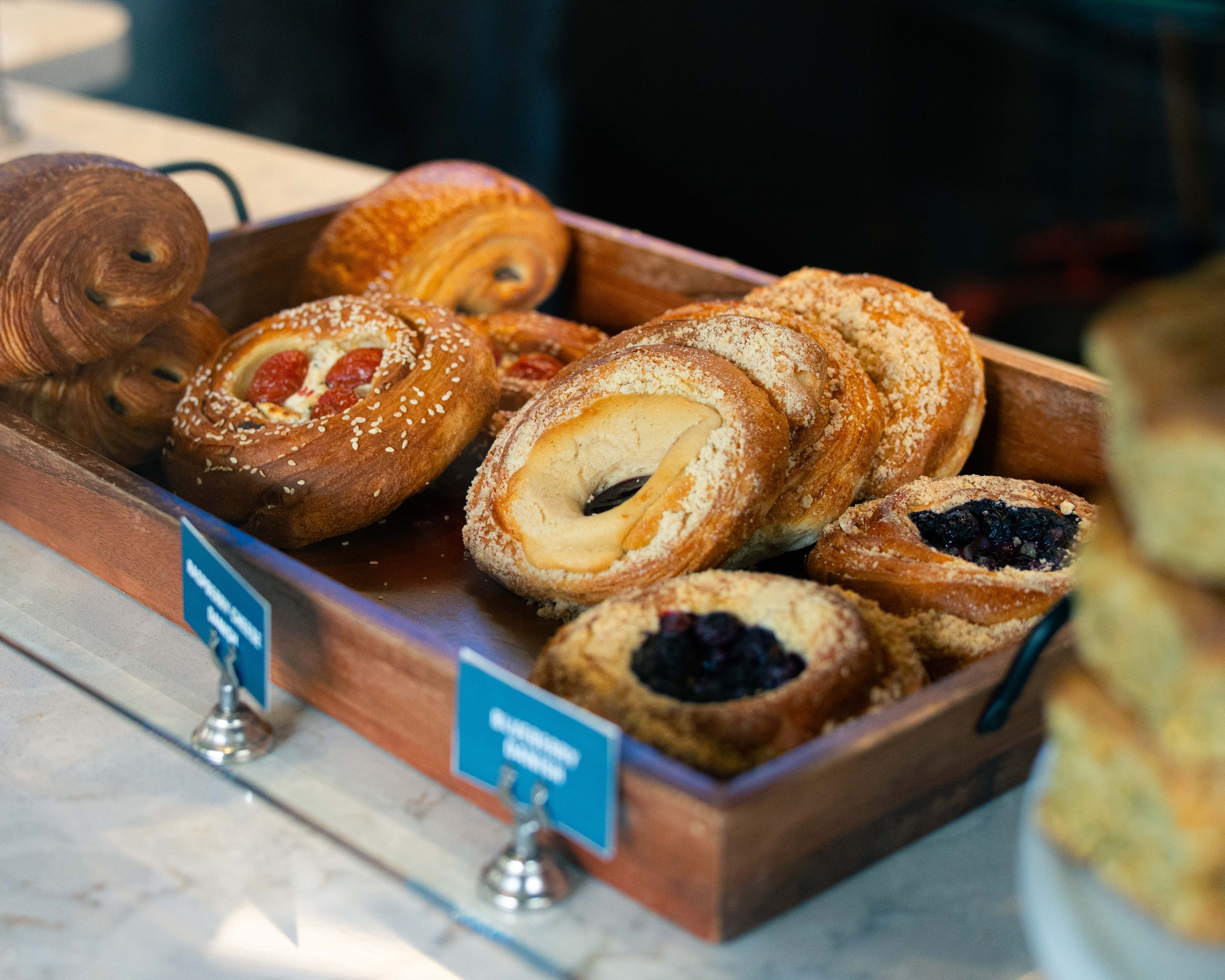 Assorted pastries in a wooden display case with name tags.