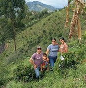 Family of four standing in a lush green landscape with mountains in the background
