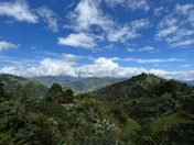 Scenic view of lush green mountains under a blue sky with white clouds