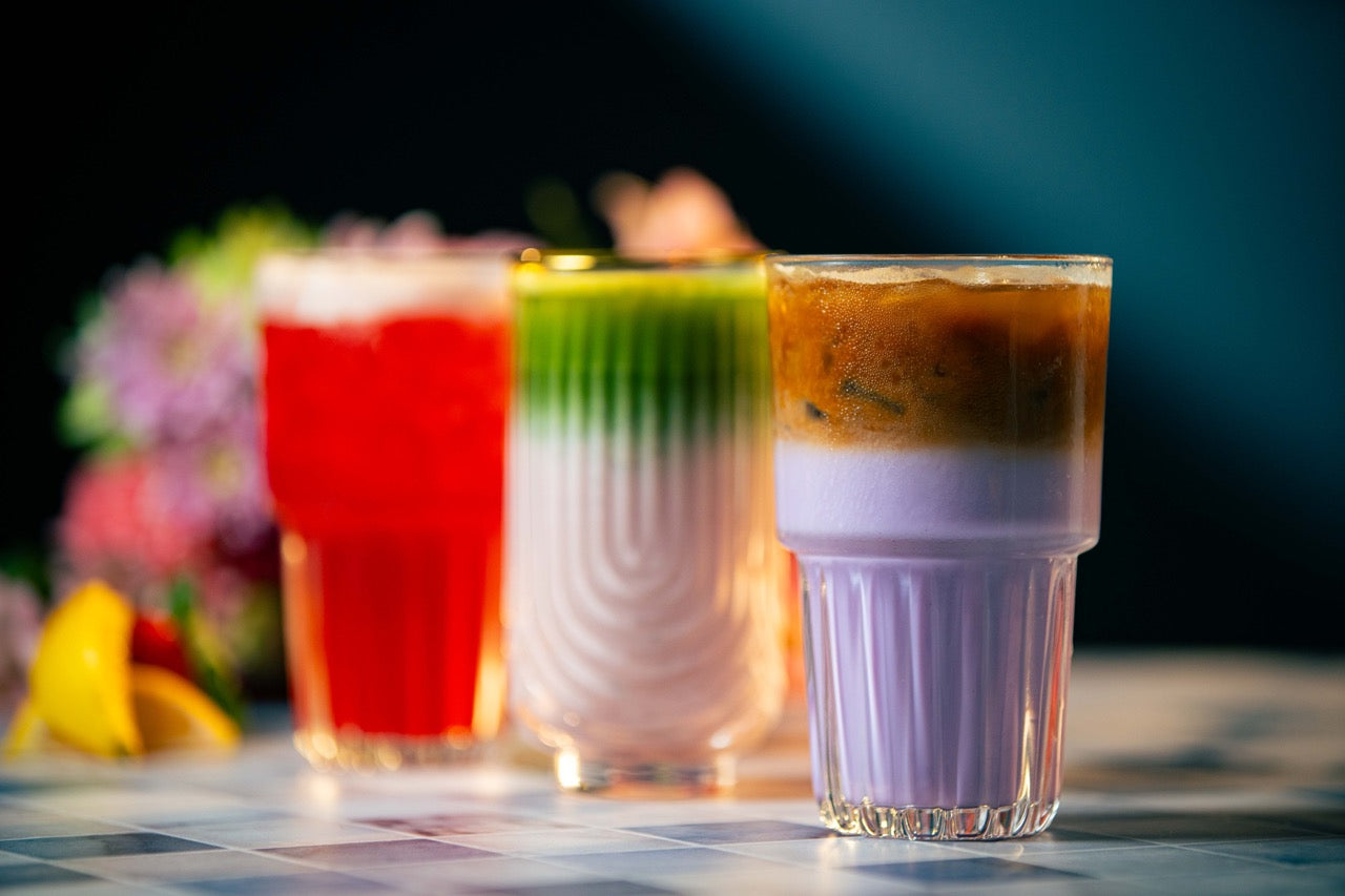 Three colorful drinks in glasses on a checkered tablecloth with a blurred background