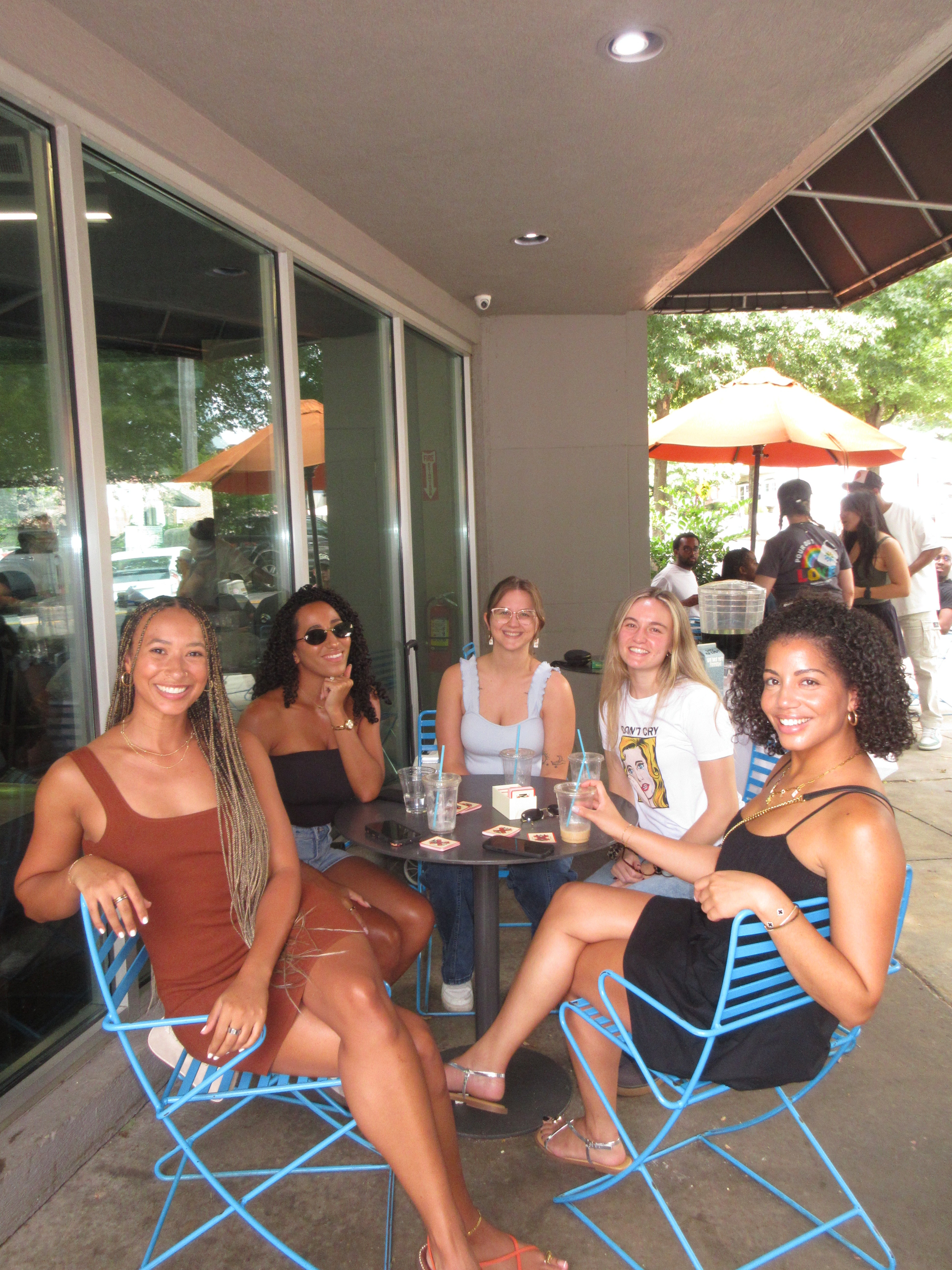 Group of women posing together outdoors near a building entrance.