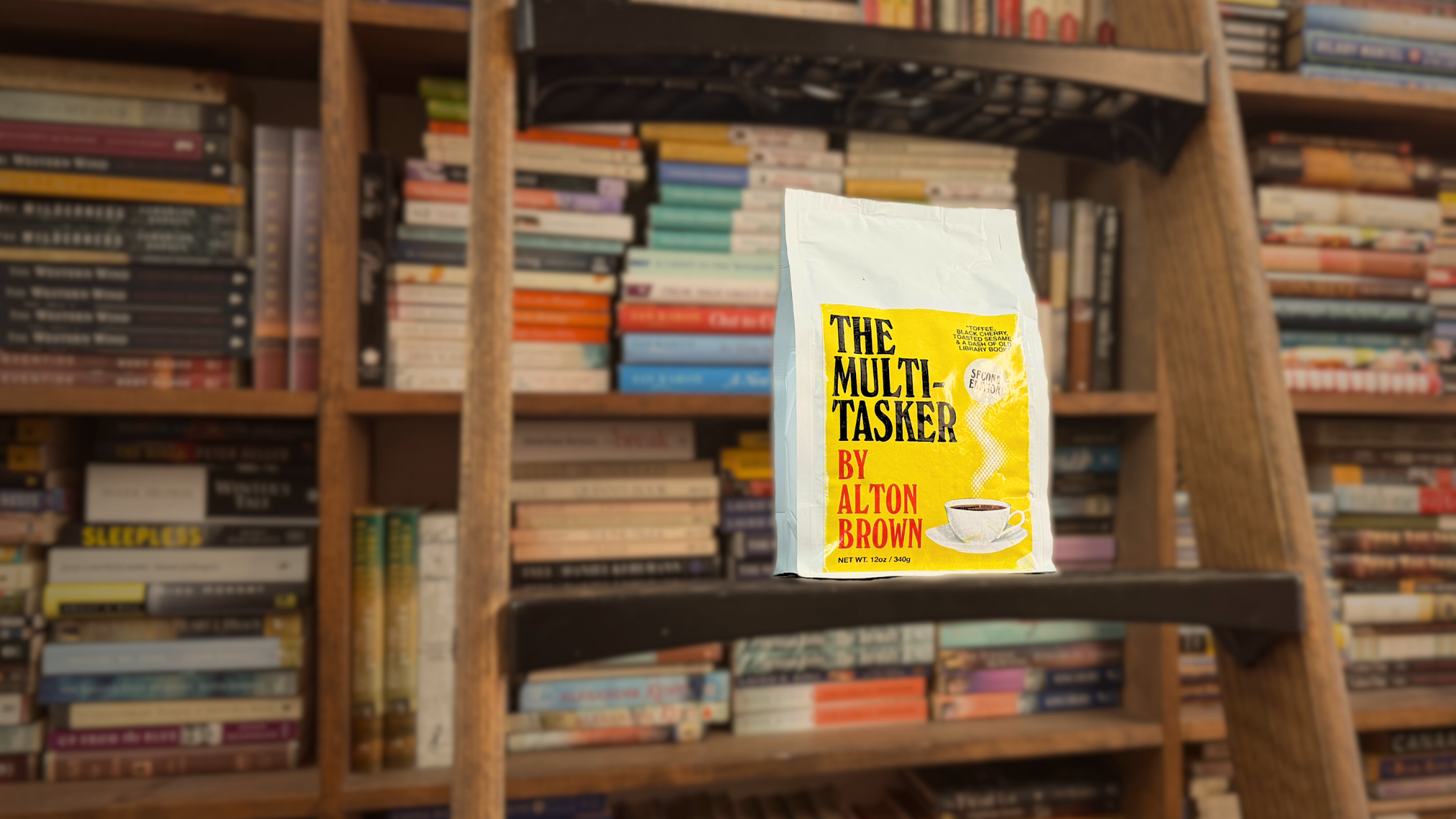 Bag of coffee 'The Multi-Tasker' by Alton Brown on a bookshelf.