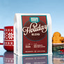A 12oz bag of Dancing Goats Holidau Blend with a cookie and a festive mug