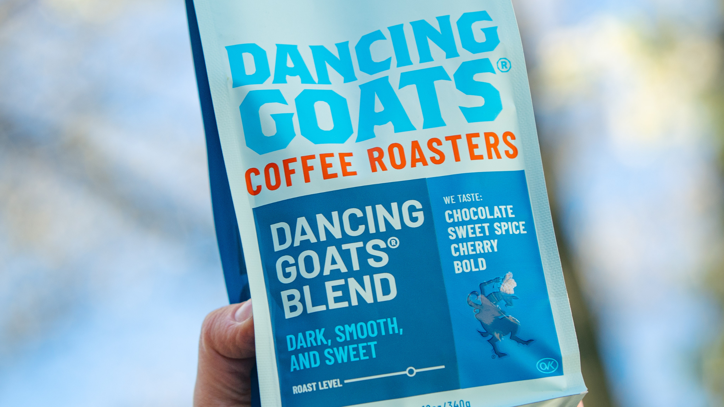 Dancing Goats Coffee Roasters package held in a hand with a blurred background