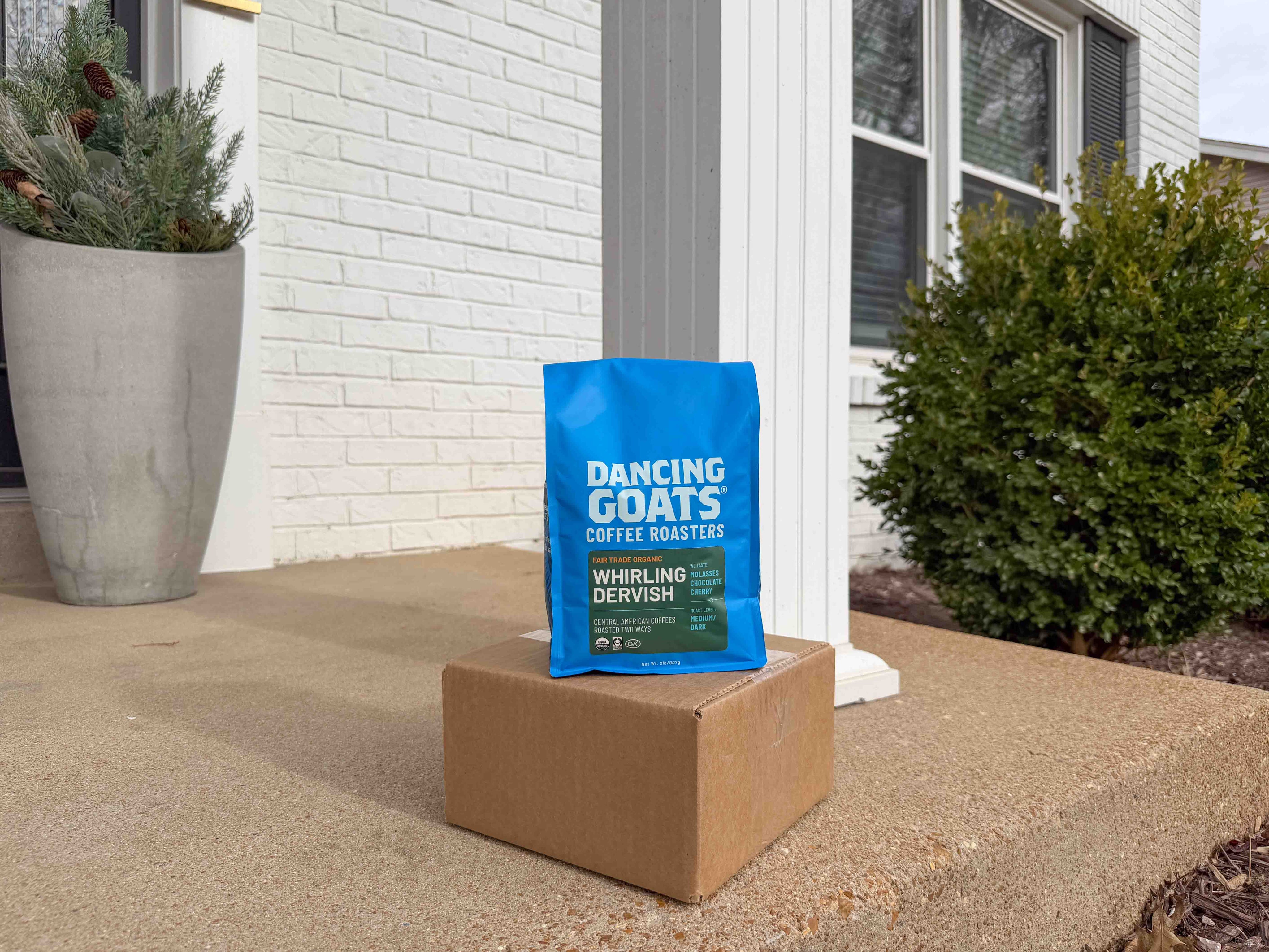 image of Blue bag of 'Dancing Goats' coffee on a cardboard box outside a house.