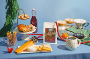 Table setting with holiday-themed coffee and snacks on a blue tablecloth.