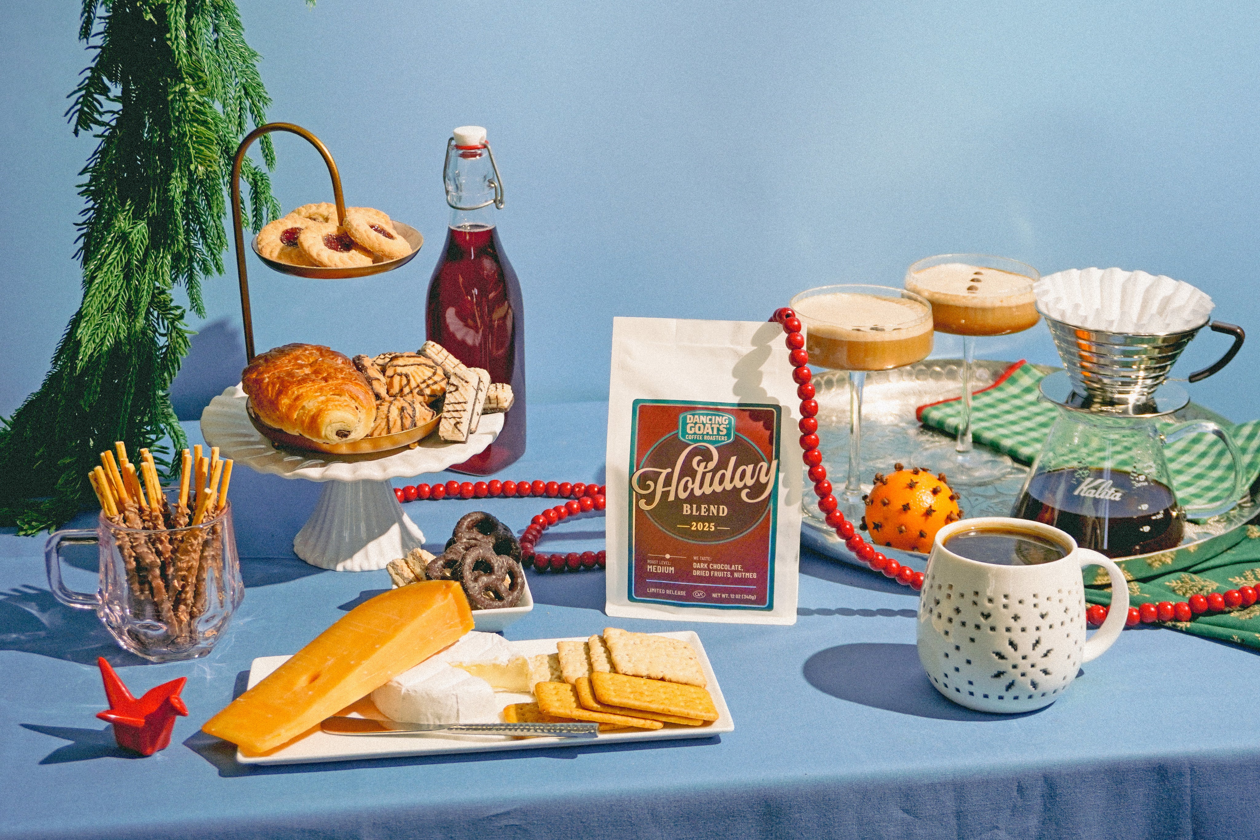 Table setting with holiday-themed coffee and snacks on a blue tablecloth.